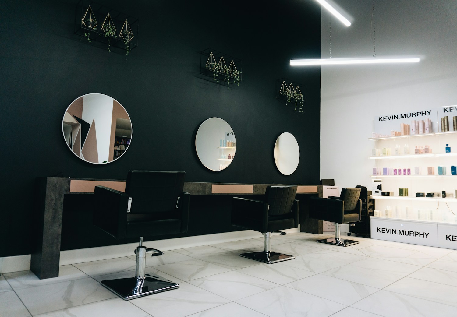 Interior de um salão de beleza com poltronas de couro e espelhos iluminados